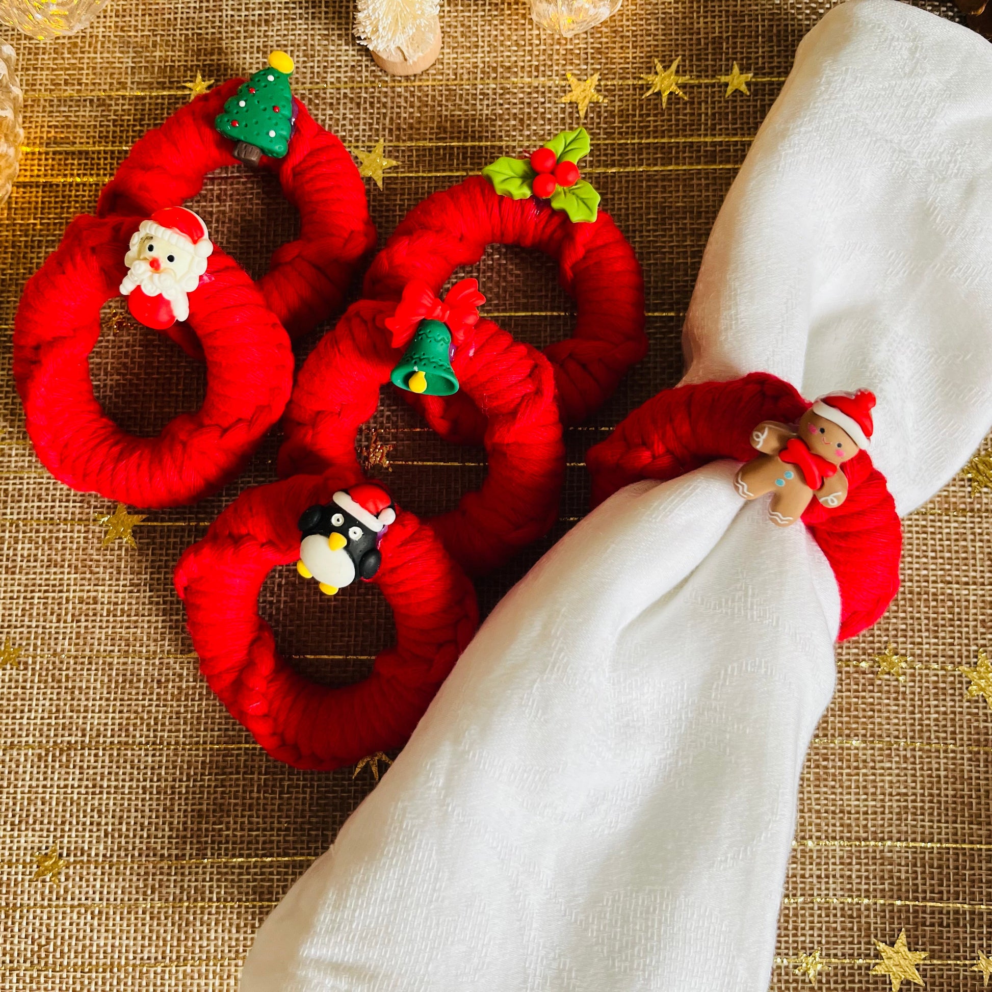 Red Christmas-themed macrame napkin rings with festive decorations on a textured surface.