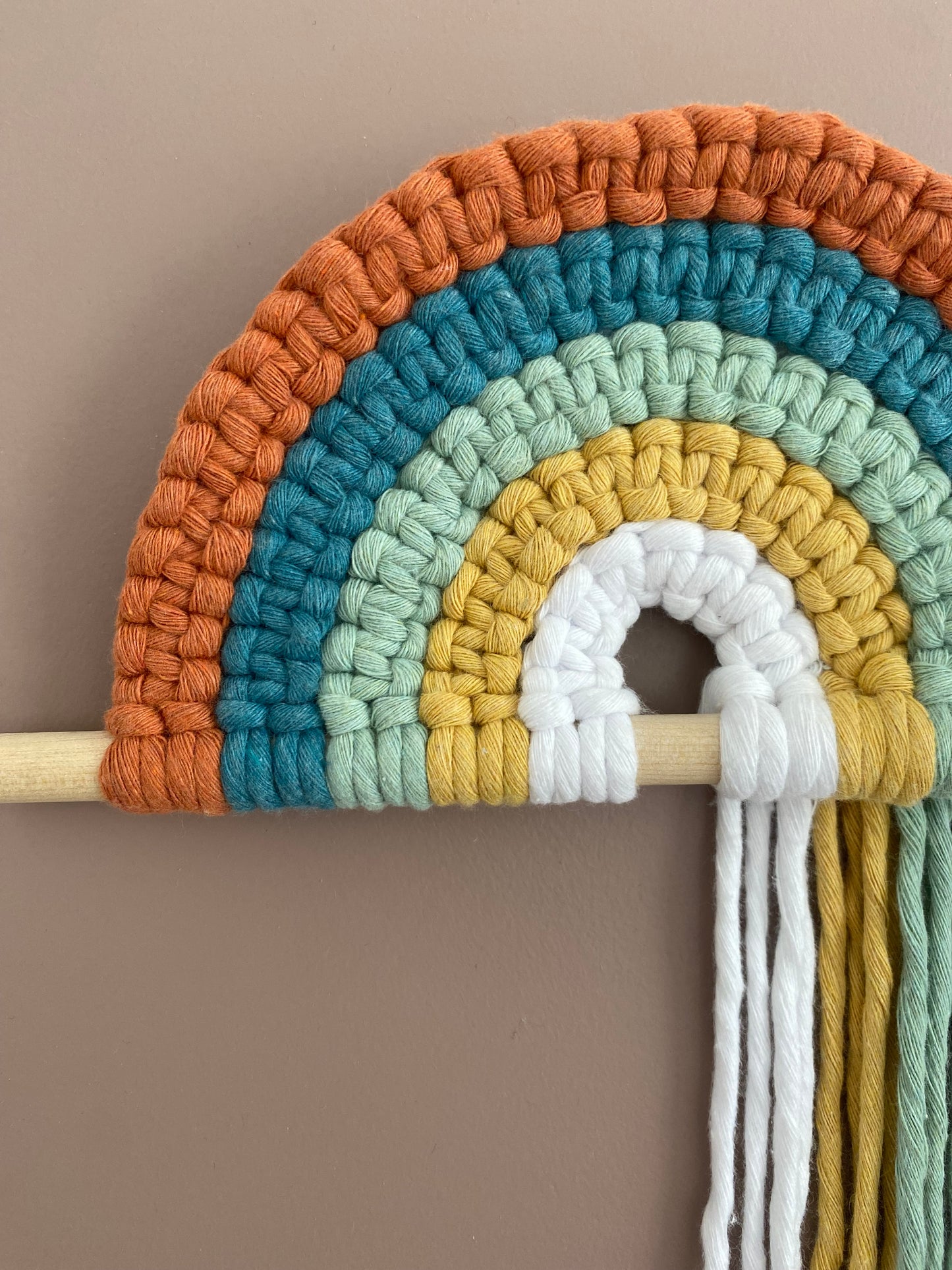 Colorful macramé rainbow on a wooden dowel