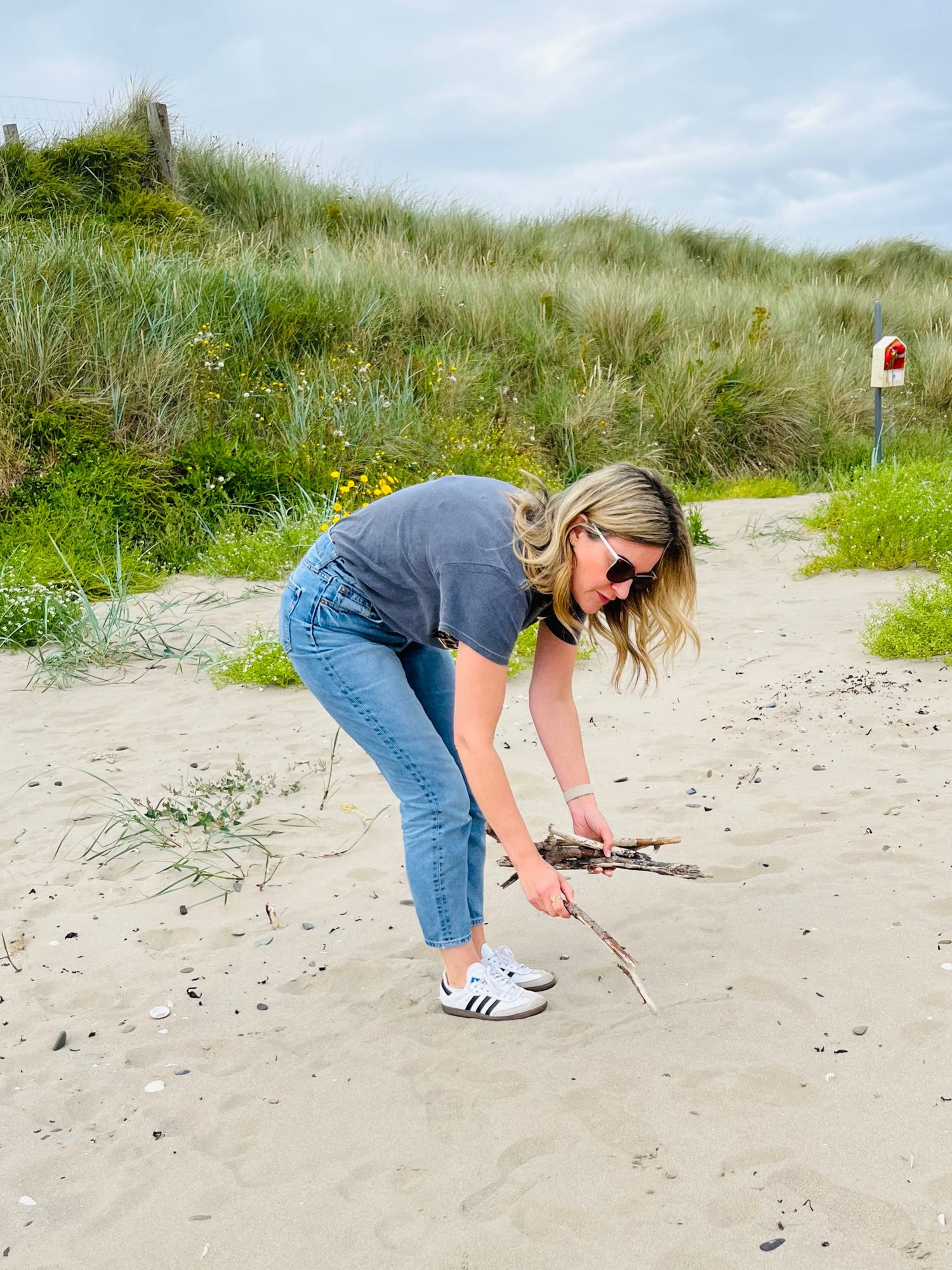 Person on a sandy beach collecting driftwood