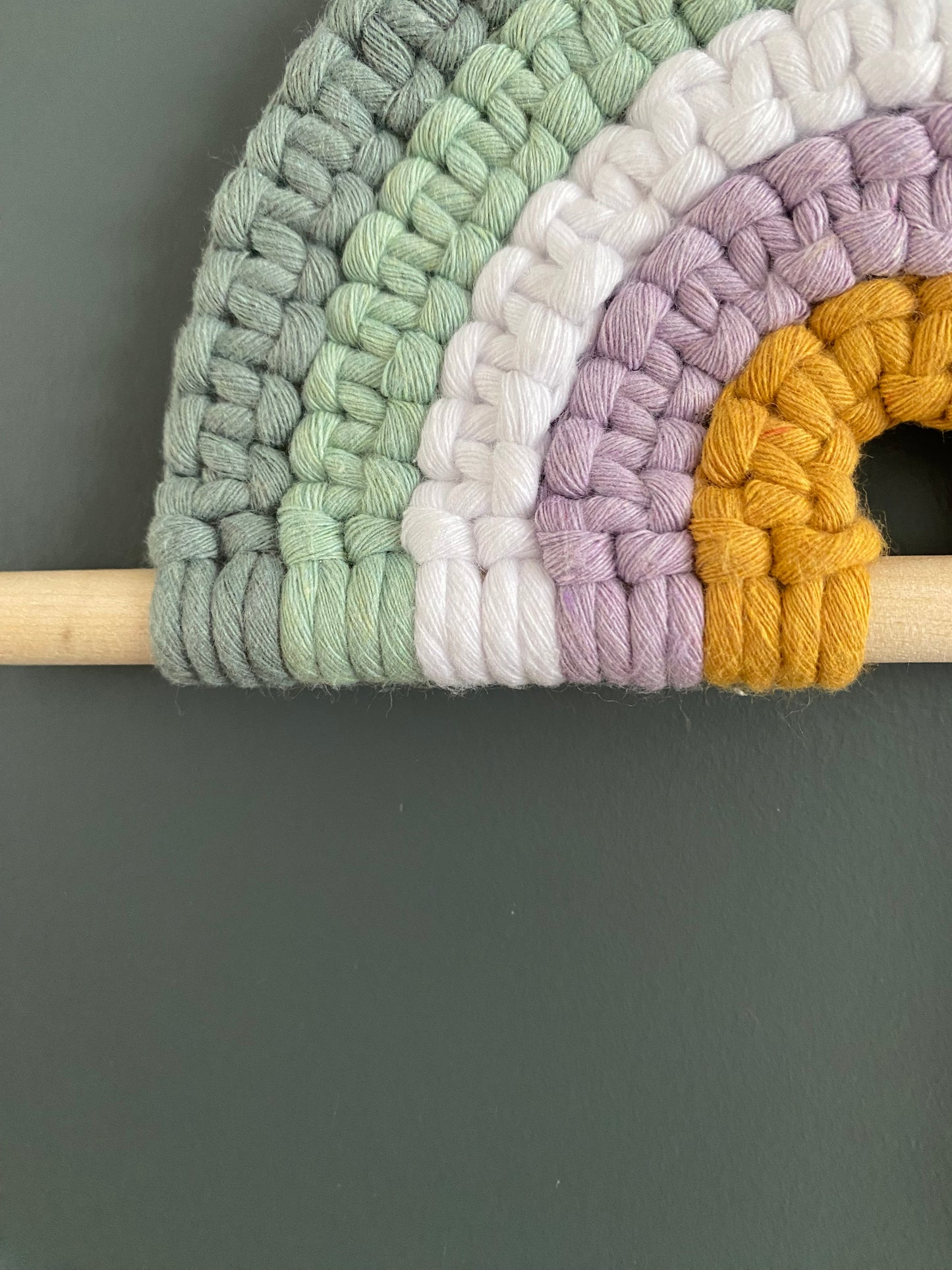 Colorful macramé rainbow on a wooden dowel 