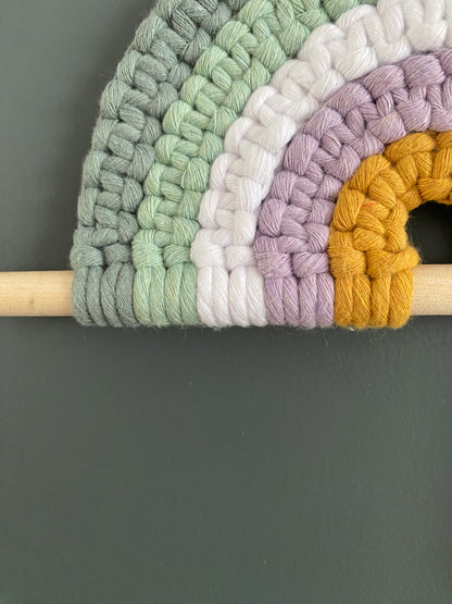 Colorful macramé rainbow on a wooden dowel 