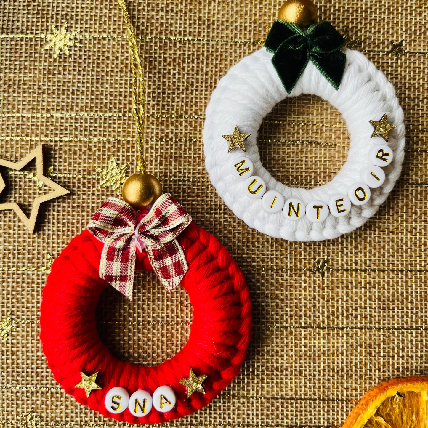 Two decorative wreaths, one red and one white, on a textured brown background.