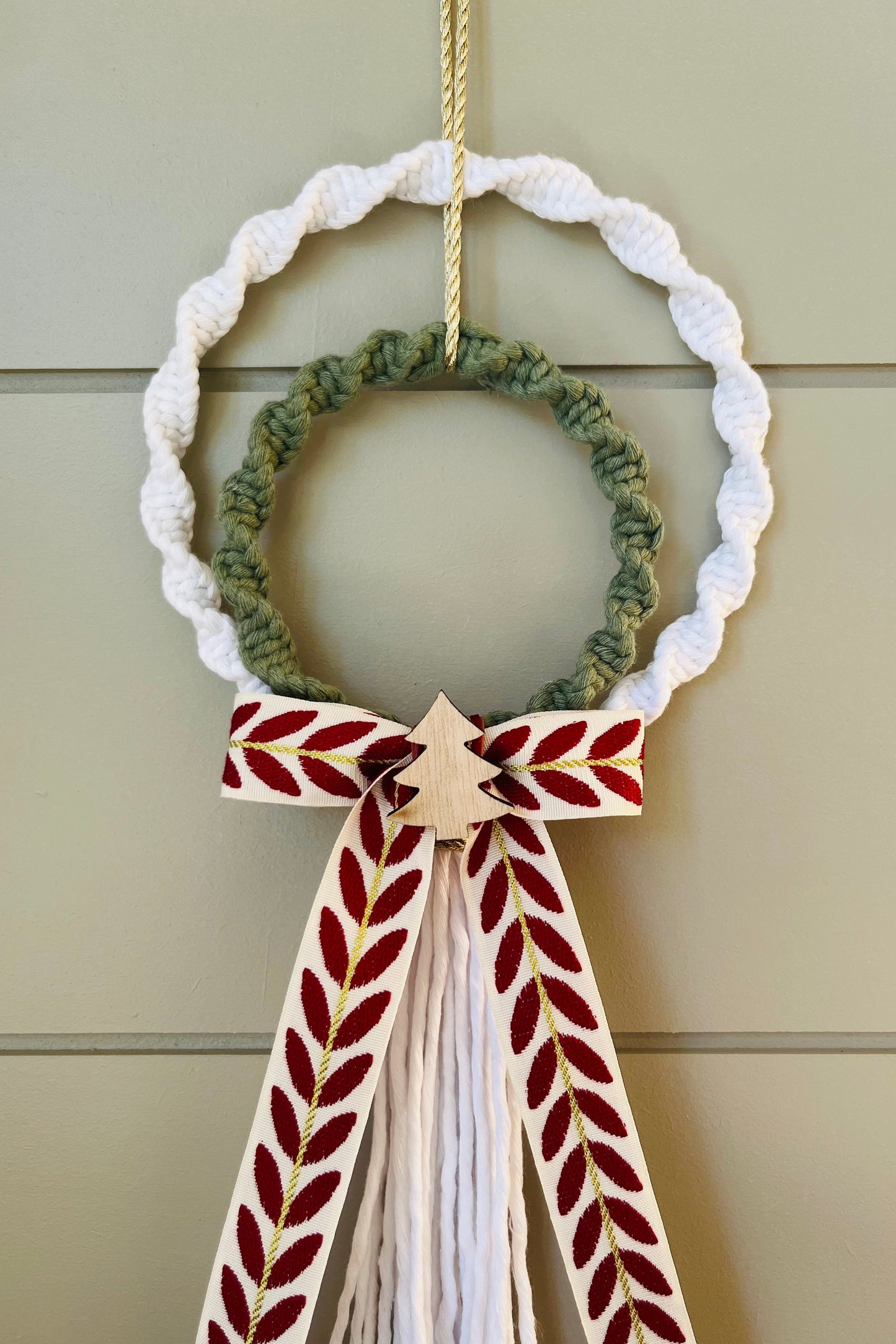 Decorative macrame Christmas wreath with tassels and a bow on a plain background