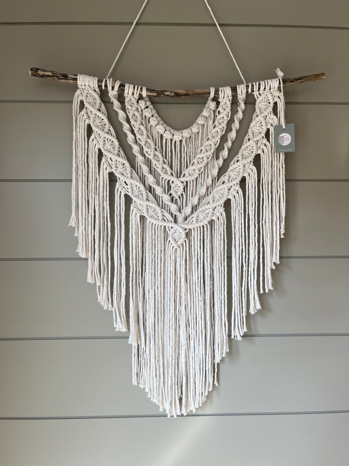 Decorative macramé boho wall hanging on a wooden panel background