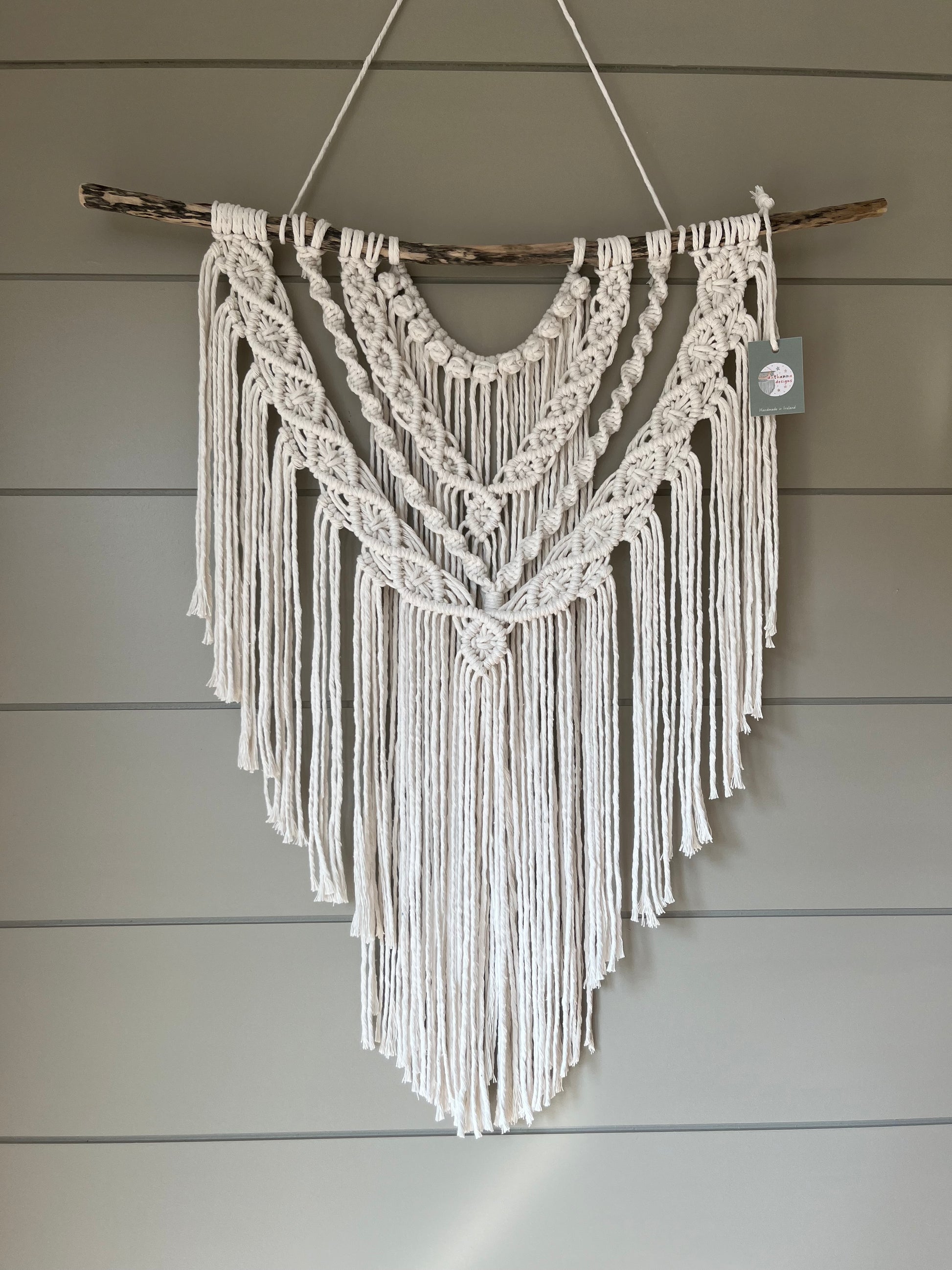 Decorative macramé boho wall hanging on a wooden panel background