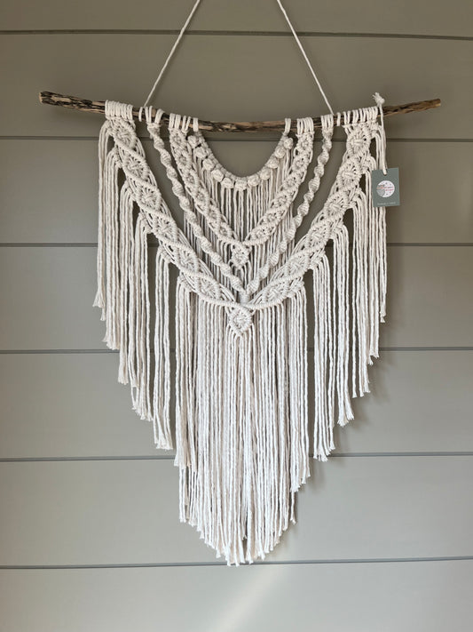 Decorative macramé boho wall hanging on a wooden panel background