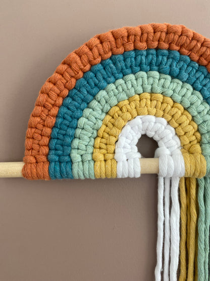 Colorful macramé rainbow on a wooden dowel 